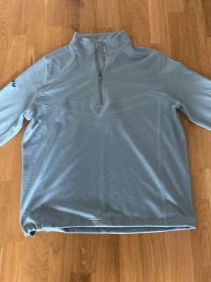 Ljusblå halvzip tröja Callaway - Ljusblå långärmad tröja från Callaway chim Weather Series med halv dragkedja framtill och hög kr sop. Tillverkad i ett tekniskt, rutsliknande material som andas. sop. Perfekt för lager-på sign och sportiga aktiviteter. Nypris 1099kr