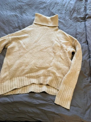 Beige stickad tröja med hög krage  - Beige stickad tröja med hög krage och raka ärmar 