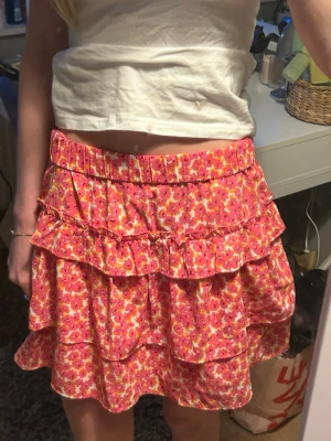 Blommig volangkjol i rosa, gul och orange - Supersöt kort volangkjol med blommigt mönster i rosa, gul, orange och vitt. Kjolen har flera lager volanger och resår i midjan för en bekväm passform. Perfekt för vår och sommar! Tyvärr är den för stor för mig därav säljer jag den😊jag är öppen för att sänka priset så lägg prisförslag om det är dyrare än vad du vill betala! Hör av dig om du undrar något💞Orginalpris 569kr