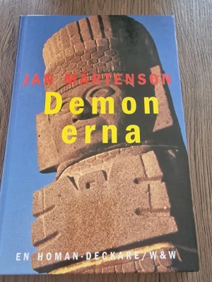 Demonerna av Jan Mårtenson - Säljer boken 'Demonerna' av Jan Mårtenson, en Homan-deckare med färgstarkt omslag och motiv av en förhistorisk mexikansk skulptur. Boken är inbunden och har en spännande handling med både naturliga och övernaturliga mordfall.