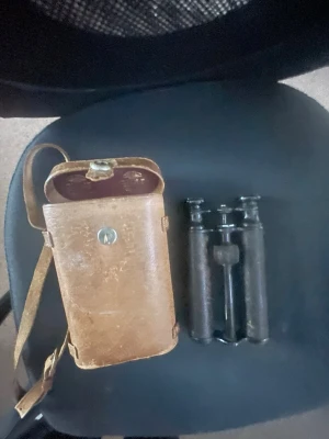 Vintage kikare med läderfodral - Säljer en klassisk svart kikare i metall med tillhörande brunt läderfodral. Kikaren har en smal och avlång sopistikerad design och fodralet har axelrem och tryckknapp. multiverktyg för kameraentusiaster eller mer  retrostil.