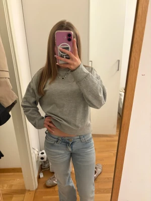 Grå sweatshirt från H&M Divided - En basic grå sweatshirt från H&M Divided i storlek XS. Tröjan har rund hals, ribbade muddar vid ärmslut och nederkant samt en avslappnad passform. Perfekt till jeans eller mjukisbyxor för en chill look.