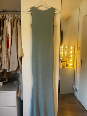 Ljusblå långklänning i stickad stil - Säljer en ljusblå långklänning i stickad stil med ärmlös design och djup urringning i ryggen. Klänningen har en smal passform och är perfekt för dig som gillar en enkel men elegant look. Materialet känns mjukt och följsamt.