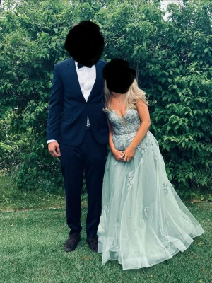 Ljusgrön balklänning med spetsdetaljer - Drömmig ljusgrön långklänning med vackra spetsapplikationer och blommiga detaljer. Klänningen har en voluminös kjol i flera lager tyll och markerad midja. Perfekt för bal eller speciella tillfällen.