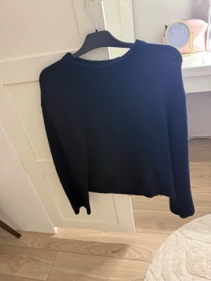 Mörkblå stickad tröja - En enkel mörkblå stickad tröja med rund hals och långa ärmar. Tröjan har en rak passform och är tillverkad i ett mjukt material som passar perfekt till höst och vinter. Stilren och lätt att matcha med olika outfits.