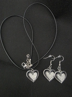 Halsband och örhängen med hjärtan - Säljer ett handgjort matchande set med halsband och örhängen i silverfärg med glittrande hjärtan. Halsbandet har en svart läderimitation och hjärtformade hängen med gnistrande detaljer. Perfekt för dig som gillar romantiska accessoarer.