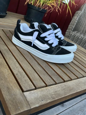Svarta Vans Old Skool sneakers - Säljer ett par klassiska Vans Old Skool sneakers i svart mocka och canvas med vit sula och vit sidostripes. Skorna har vita skosnören och kontrastsömmar som ger en snygg streetwear-look. Perfekta för dig som gillar stilrena och tidlösa sneakers.