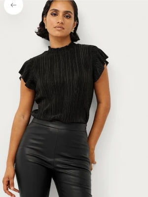 Svart plisserad blus med volangärm - Svart blus med korta volangärmar från Ellos. Köpt för 249kr, prislapp borta men ej använd🌸