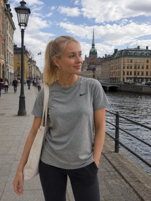Grå Nike t-shirt i bomull - Snygg grå t-shirt från Nike med klassisk svart swoosh-logga på bröstet. T-shirten har rund halsringning och korta ärmar. Tillverkad i mjuk bomull som är skön att bära till vardags eller träning.