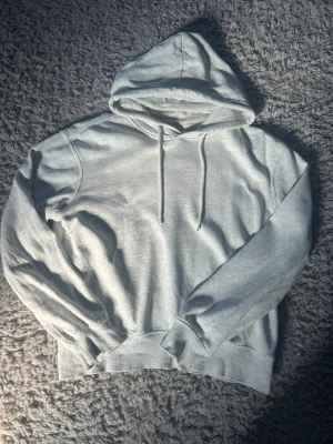Ljusgrå hoodie med huva och tryck - Ljusgrå hoodie med huva och dragsnören i ett tunnare material. Diskret tryck med texten 'LOVE' på bröstet. Tillverkad i mjukt sweatshirtmaterial och har ribbade muddar vid ärmslut och nederkant. Perfekt för en avslappnad och stilren look. Liten blå fläck precis vid ena axeln (se sista bilden) men inget man tänker på enligt mig💕 säljer då jag har alldeles för många hoodies 