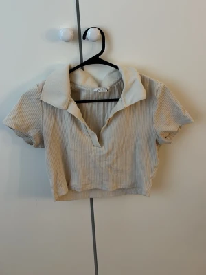Beige ribbad croppad topp  - Trendig kort croppad topp från Monki i beige ribbat material. Väldigt elegant och snygg. Gåva vid köp!🎁