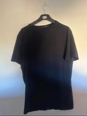 Svart t-shirt från Morris - En stilren svart t-shirt från Morris i klassisk modell. T-shirten har rund halsringning och korta ärmar. Tillverkad i mjuk bomull som känns skön mot huden. Perfekt basplagg för en enkel och clean look.