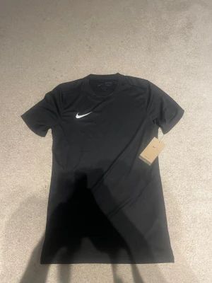 Svart Nike Dri-FIT t-shirt - Säljer en helt ny Nike t-shirt som passar perfekt t gymmet eller fotbolls träningar eller liknande . Det är storlek S i model slim fit. Säljer då den inte passade . Helt ny med lapp kvar .
