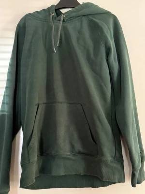 Mörkgrön hoodie ifrån Carhartt storlek S - Säljer en mörkgrön luvtröja ifrån Carhartt, använd ett få tal gånger men har blivit väll omhändertagen. Nypris 900kr  