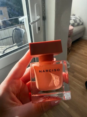 Narciso Amberee 30ml - Säljer en Narciso parfym i en snygg, fyrkantig glasflaska med persikofärgad insida och matchande lock. Flaskan har en modern och stilren design som känns lyxig och trendig. Perfekt för dig som gillar eleganta och unika dofter.