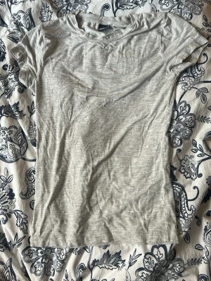 Ljusgrå basic t-shirt  - En enkel och stilren ljusgrå t-shirt från Gina Tricot . T-shirten har rund halsringning och korta ärmar. Tillverkad i mjuk bomull för en bekväm känsla och passar perfekt till alla typer av outfits.