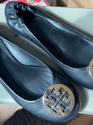 Svarta ballerinaskor från Tory Burch - Stilrena svarta ballerinaskor i läder från Tory Burch med rund tå och elastisk häl. Aldrig använda.