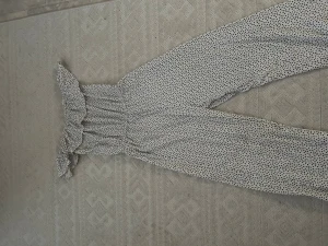 Prickig off-shoulder jumpsuit - Supersöt jumpsuit med svartvita prickar och bred volang upptill. Off-shoulder modell med resår i midjan för en snygg siluett. Långa ben och luftig passform, perfekt för en trendig och avslappnad look.