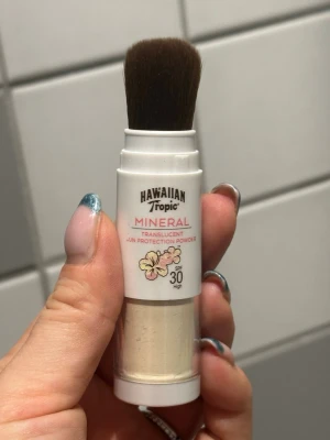 Hawaiian Tropic Mineral Foundation - Endast testad!!   Transparant mineralpuder från Hawaiian Tropic med inbyggd borste och SPF 30. Förpackningen är vit med blommig detalj och puder i ljus, neutral ton. Perfekt för enkel applicering och solskydd i ett steg.  