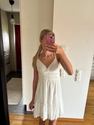 Sommarklänning  - Skön och luftig sommarklänning i vit som är perfekt till midsommar, sommarfester men även som en strandklänning. Öppen rygg med band som går att spänna in och ut. 