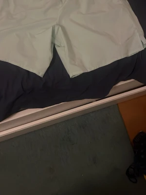 Ljusblå Nike shorts i syntet - Snygga ljusblå shorts från Nike med klassisk logga på benet. Tillverkade i ett lätt syntetmaterial som passar perfekt för träning eller varma dagar. Enkel och stilren design med normal passform.