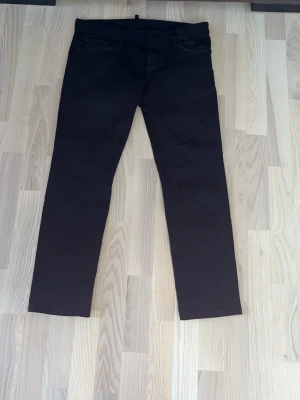 Svarta raka jeans - Svarta jeans med rak passform och klassisk femficksdesign. Jeansen har en stilren look och passar perfekt till en avslappnad streetstyle. Materialet ser ut att vara bomullsblandning med lite stretch för extra komfort.