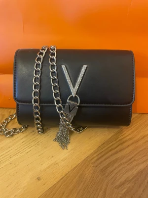 Valentino väska  - Snygg svart axelväska i läderlook från Valentino som passar till allt! Väskan har ett huvudfack, kortfack och innerficka. Smidig och perfekt för att lyfta din outfit med en lyxig touch.