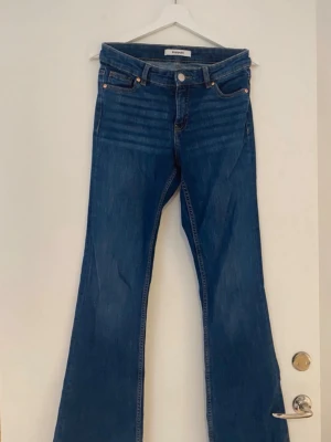 Blå bootcut jeans från kappahl - Snygga blå bootcut jeans från kappahl med klassisk femficksdesign och normal midja. Jeansen har en lätt utsvängd passform nertill och är tillverkade i denim med en autentisk blå tvätt. Perfekta för en trendig och avslappnad look. Använd fåtal gånger