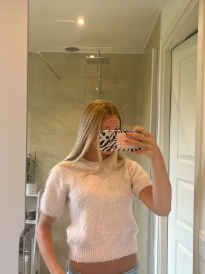 Ljusrosa stickad kortärmad tröja - Mysig ljusrosa stickad tröja med korta ärmar och ribbade muddar vid ärmslut och nederkant. Tröjan har en mjuk, fluffig känsla och rund halsringning. Inte använd många gånger och inga defekter.