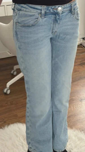 Ljusblå utsvängda jeans från Gina Tricot - Säljer ett par ljusblå jeans från Gina Tricot med rak passform och klassisk femficksdesign. Jeansen har normal midja, bälteshällor och stängs med knapp och dragkedja. Tillverkade i denim med snygg tvättad look.