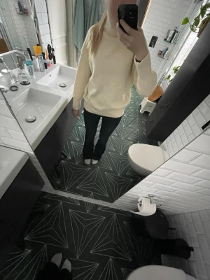 Krämvit polotröja stickad - Mysig krämvit stickad polotröja med avslappnad passform och långa ärmar. Tröjan har en hög polokrage och är perfekt för lager på lager. Materialet ser ut att vara mjukt och bekvämt, troligen bomull eller akryl.