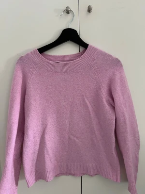 Rosa stickad tröja från Vero Moda - Mysig rosa stickad tröja med rund halsringning och långa ärmar. Perfekt för lager på lager och enkel att matcha med jeans eller kjol. Använd men fortfarande i bra skick!
