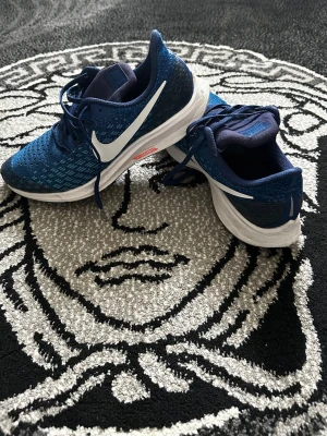 Blå Nike sneakers med mesh - Säljer ett par blå Nike sneakers med ventilerande mesh-ovandel och vita detaljer på sulan. Skorna har klassisk snörning och sportig design som passar perfekt till streetwear eller träning. Lätta och bekväma för en aktiv livsstil.