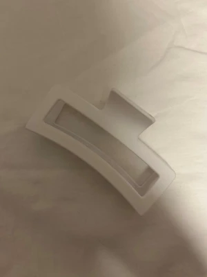 Vit stor hårklämma i rektangulär form - Stilren stor vit hårklämma med rektangulär design och öppet mittparti. Tillverkad i plast och perfekt för att hålla upp håret på ett snyggt sätt. 