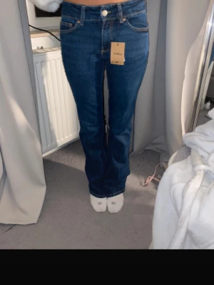 Mörkblå bootcut lowwaist jeans från H&M - Säljer ett par mörkblå bootcut jeans från H&M med klassisk femficksdesign och låg midja. Jeansen har en snygg tvätt och är tillverkade i stretchigt denim för skön passform. Perfekta för dig som vill ha en tidlös och trendig look.