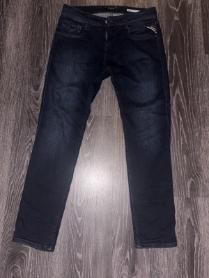 Mörkblå slim fit jeans från Replay - Tjena! Säljer nu ett par snygga mörkblå slim fit jeans från Replay, modell Anbass. Skicket är mycket bra då de är väldigt sparsamt använda. Storleken är 30/30, nypris- 1400 kr. Mitt pris 650 kr. Vid intresse eller fler bilder är det bara att skriva (: