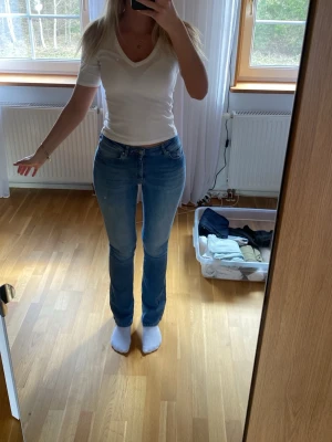 Ljusblå bootcut jeans - Säljer ett par ljusblå bootcut jeans med klassisk femficksdesign och normal midja. Jeansen har en lätt tvättad look och raka ben som går ut lite nedtill. Perfekta till en avslappnad stil och passar till det mesta i garderoben.