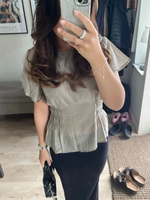 Grön blus med smock - Säljer en grön blus från H&M i storlek s med smockdetaljer i midjan. Blusen är i nyskick! ☀️