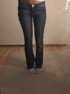 Mörkblå bootcut jeans - Säljer ett par mörkblå bootcut jeans med låg midja och klassiska fem fickor. 