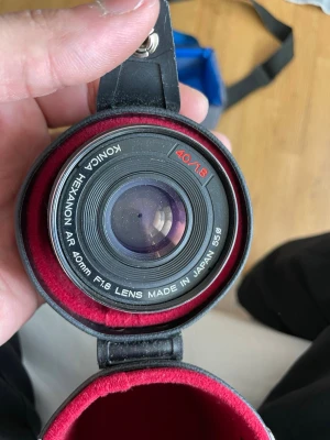 Konica Hexanon AR 40mm F1.8 objektiv - Säljer ett Konica Hexanon AR 40mm F1.8 objektiv, tillverkat i Japan. Objektivet är svart med vit och röd text, och har en klassisk rund form. Levereras i ett fodral med röd insida. Passar till analoga kameror med AR-fattning.