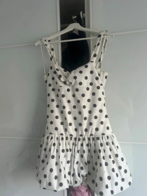  Ny Vit kort prickig klänning från Zara  - Superfin vit kort klänning med svarta prickar och axelband. Klänningen har en söt volang nertill och en lätt figurnära passform. Perfekt för varma dagar och ger en lekfull vibe. Obs det stå L på klänning etiketten men den är lite i storlek upplever som En medium därför säljer jag som en M Stl 
