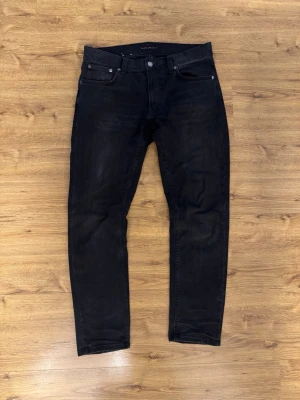 Svarta nudie jeans Lean Dean - Hej! Med en liten tår  på kinden säljer jag mina egna jeans eftersom de inte passar mig längre. Det är Nudie Jeans Lean Dean Black Eyes, eller kort och gott svart färg. Jag har haft dem sedan 6 november 2025, så de är i princip nästintill nya. Nypris 1600kr. Kvitto finns såklart! Hör av dig om du har några frågor. 