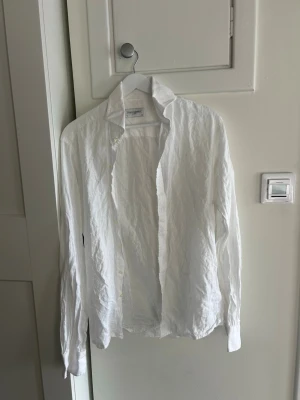 Vit linneskjorta från John Henric - Klassisk vit skjorta från John Henric i svalt och luftigt linne. Skjortan har lång ärm, krage och knappar framtill. Perfekt för en clean och stilren look, lätt att matcha med både jeans och chinos.