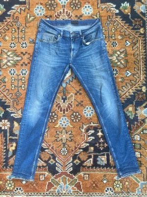 Tiger Of Sweden - Säljer ett par blå Tiger Of Sweden slim fit jeans med snygga slitningar och tvättade detaljer. Jeansen har klassisk femficksmodell, normal midja och smala ben. Materialet är mjukt denim med stretch för extra komfort. Perfekta för en avslappnad och trendig look. S 32/32. Väldigt bra skick. Nice design vid knän. Fråga om fler bilder eller mått! Prisförändringar tas gärna!