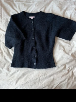 Marinblå stickad tröja - kortärmad kofta med knappar, har andvänt den två gånger och den är som ny. Storleken är 158/164 och är som XS. 