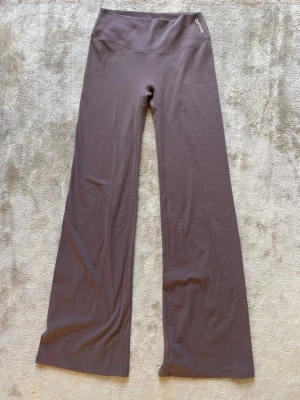 Origin flares  från DFYNE - Säljer ett par Origin flares i färgen mauve från DFYNE. Byxorna har medel hög midja och är tillverkade i ett stretchigt, mjukt material som passar perfekt för gymmet eller yoga. Diskret logga på linningen. Snygg passform och bekväma att röra sig i.