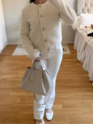  Teddykofta  - Säljer en super fin krämvit teddykofta med rund hals och stora guldknappar framtill. Koftan har en boxy passform och långa ärmar. 🤍