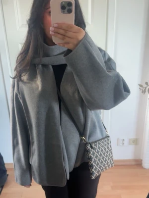 Short scarf jacket Gina tricot  - Säljer min kappa med scarf köpt från Gina tricot. Har använts max 5 gånger. Den säljs i nyskick, dvs inga märken eller fläckar på den. Kappan är i storlek XL och sitter väldigt oversized på mig. Passar perfekt till våren! 