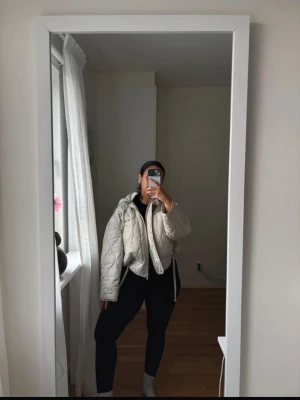 Beige quiltad pufferjacka med huva - Säljer en beige quiltad pufferjacka från Quilted Puffer. Jackan har en croppad passform, dragkedja framtill, två fickor och justerbar dragsko i nederkant. Utrustad med huva och snyggt mönstrad sömnad. Perfekt för alla säsonger