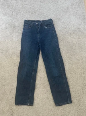 Blå 90's straight jeans från &Denim - Säljer ett par blå 90's straight jeans från &Denim med ultra high waist. Klassisk femficksmodell i kraftigt denimtyg och raka ben. 